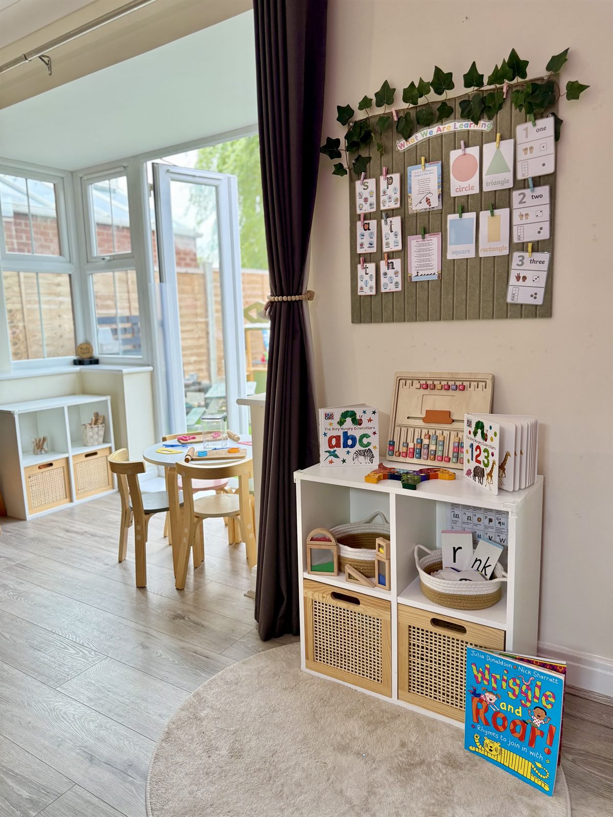 The playroom table beneath our learning display and big windows